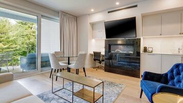 A modern living room with a sofa, chairs, a coffee table, a fireplace, and a TV.