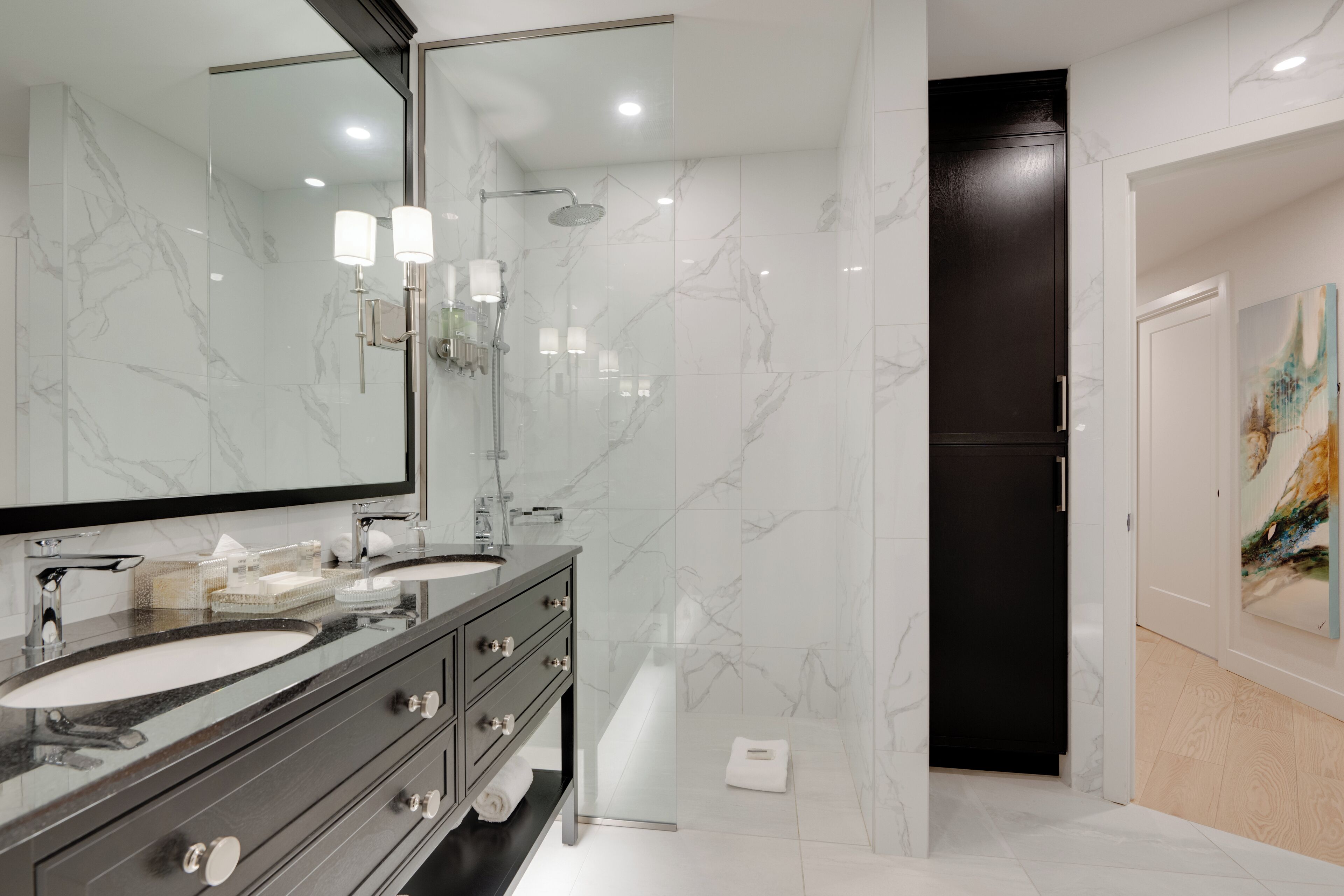 A modern bathroom with two sinks, a large mirror, and a shower.