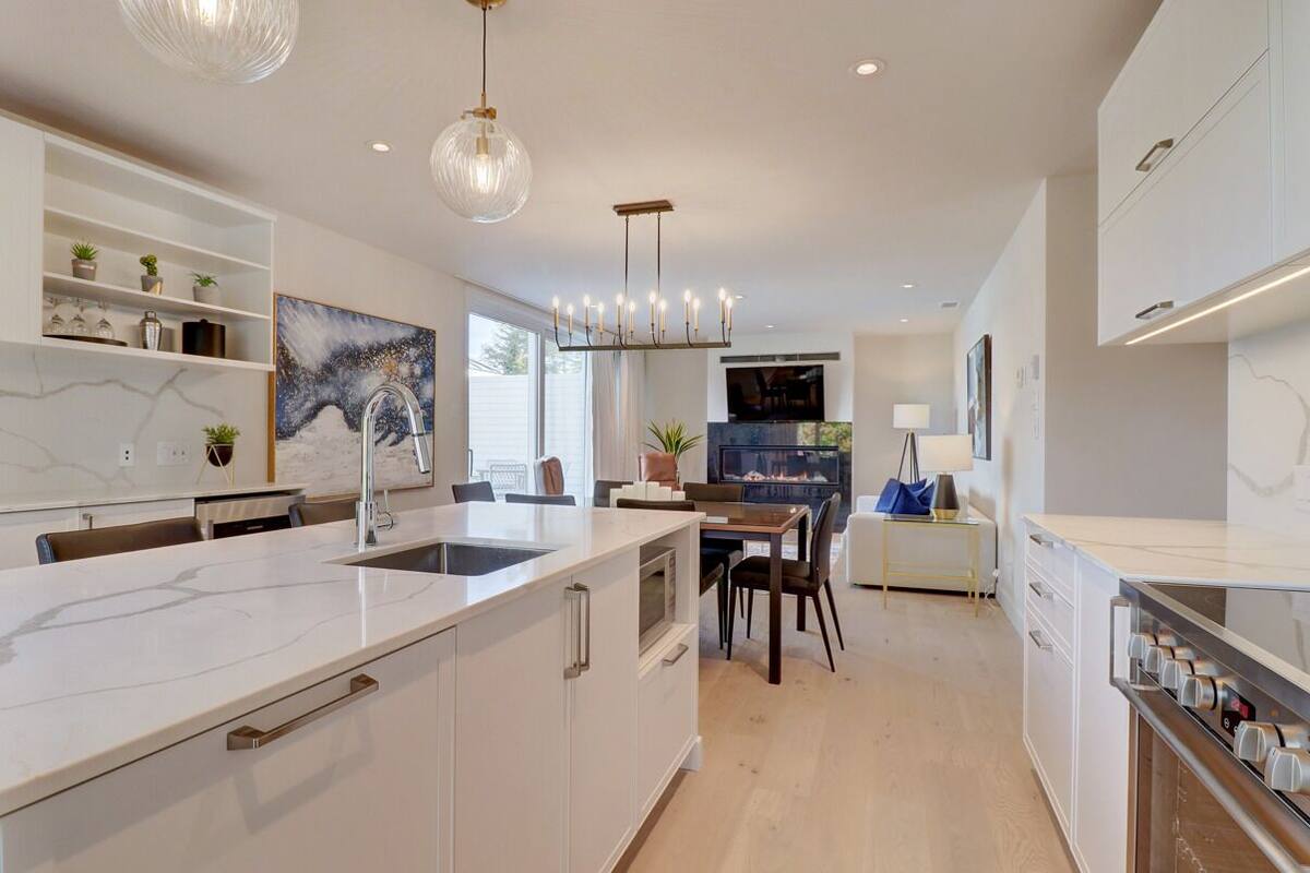 A modern kitchen with a marble countertop, built-in appliances, and pendant lighting.