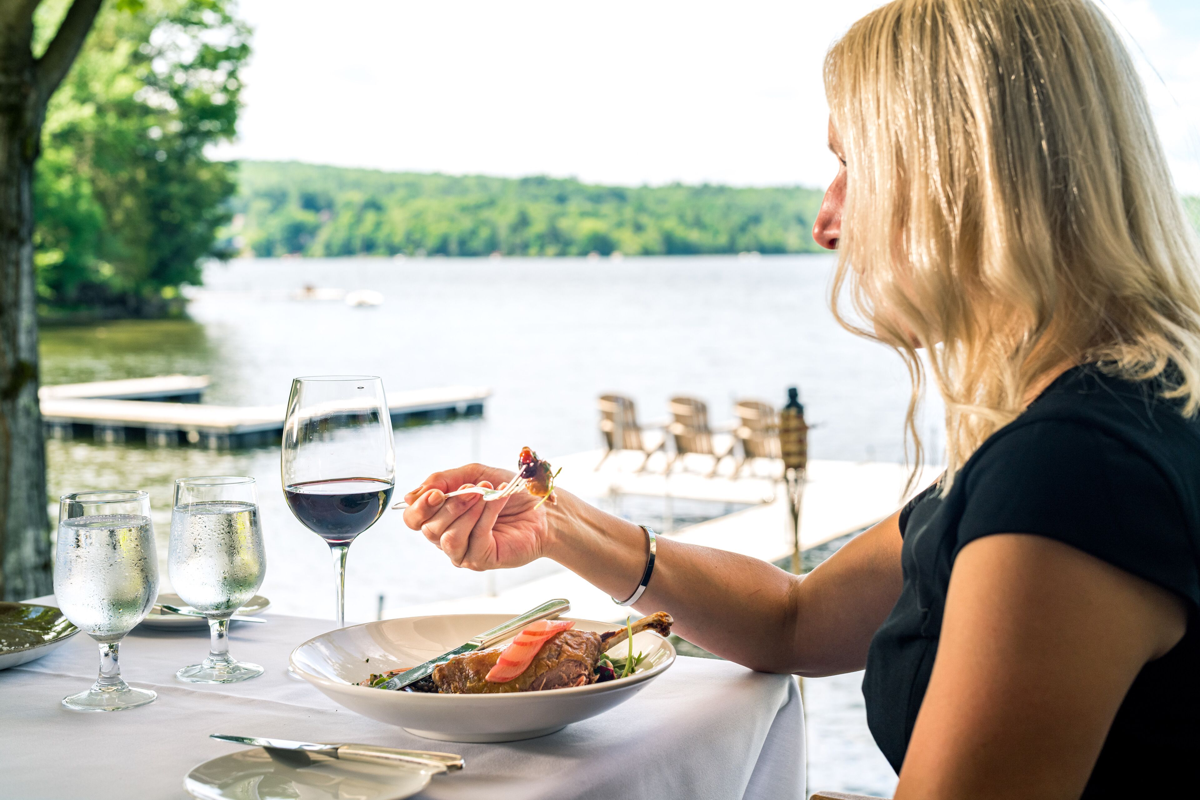 A dining table with a plate of food, glasses, and a wine glass.