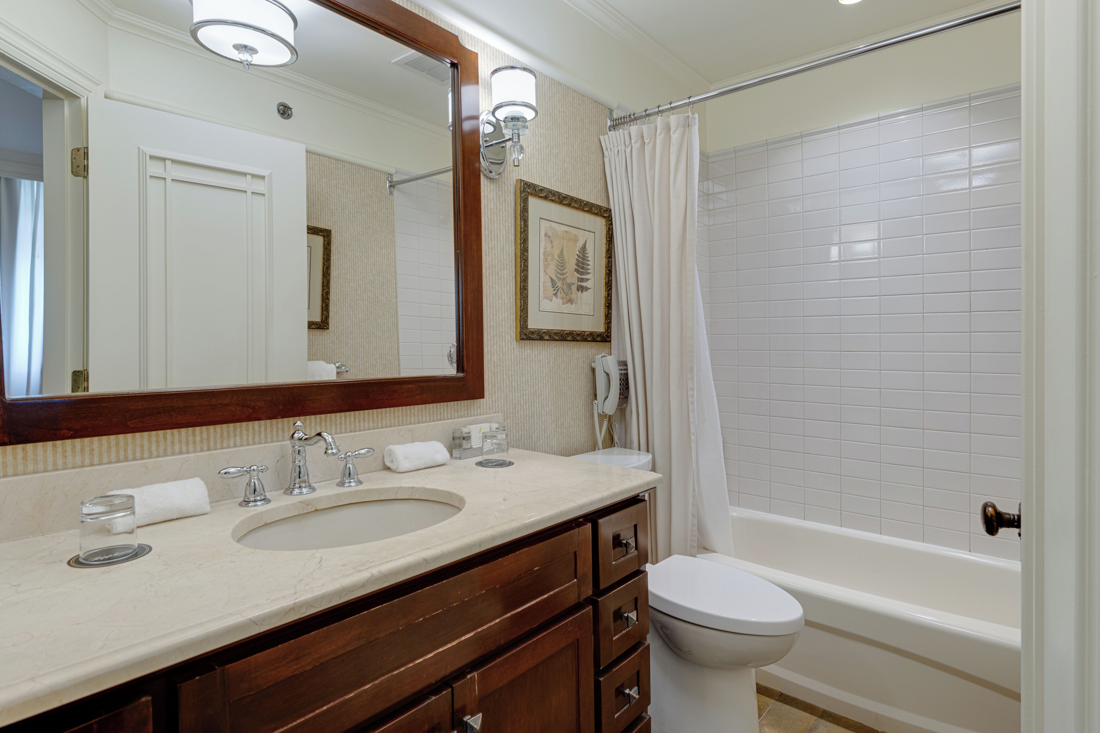 A bathroom with a sink, mirror, toilet, and bathtub.