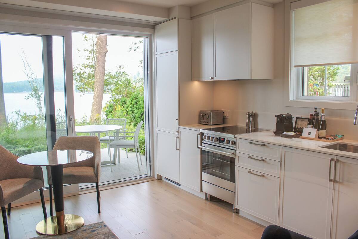 A modern kitchen with a large window, a dining table, and chairs.