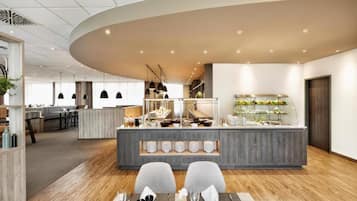 Un área de comedor moderna con una isla central, asientos y una cocina al fondo.