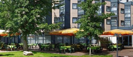 A courtyard with outdoor seating, a fountain, and a building with multiple floors and balconies.