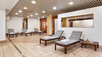 Relax in a serene spa room with lounge chairs, a large mirror, and a small table.