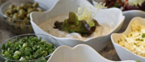 A buffet with various food items in white bowls, including salads and dips.