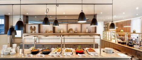 A buffet area with multiple serving stations, overhead lighting, and a variety of dishes displayed.