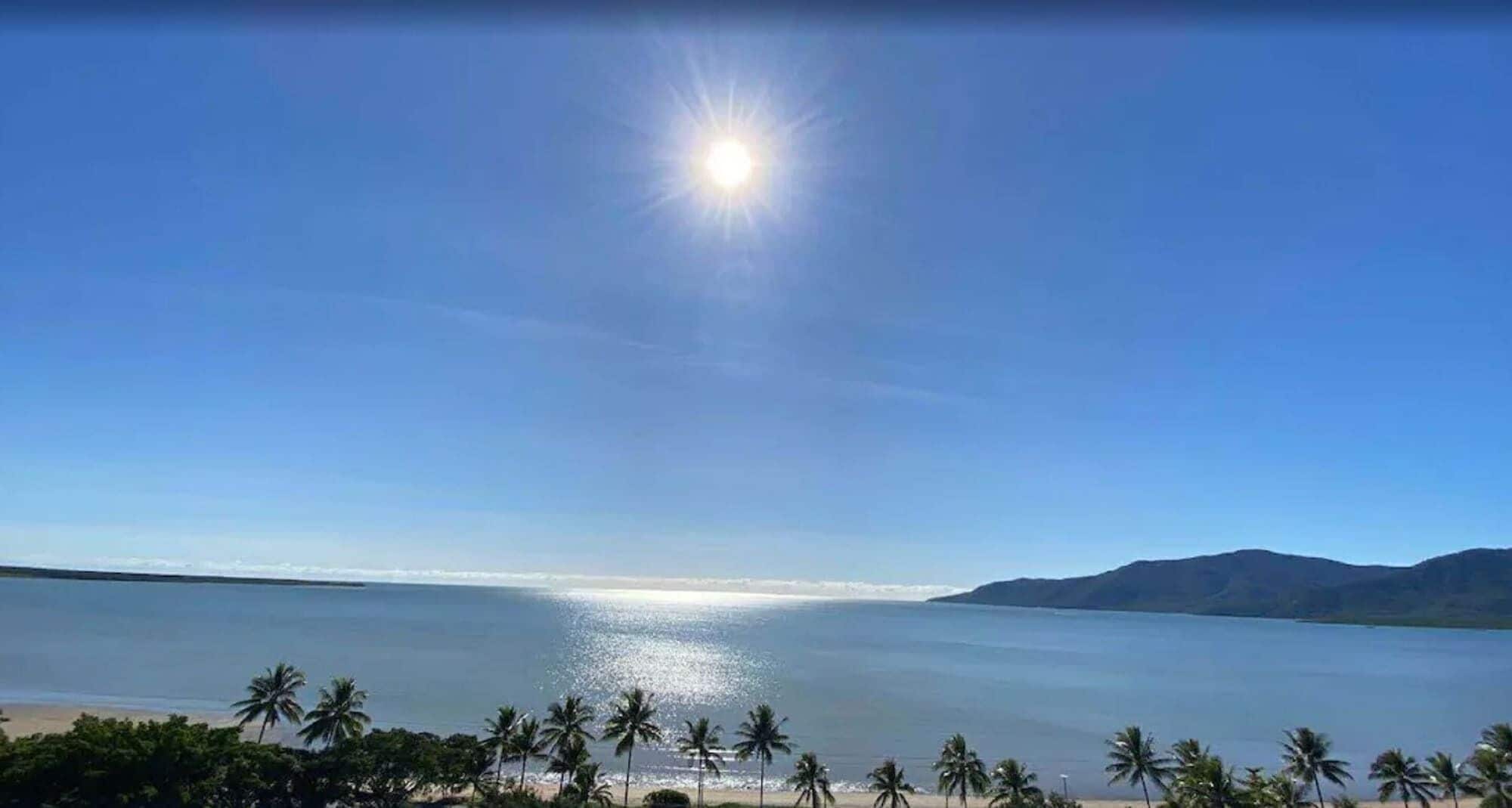 A beach with palm trees and mountains in the background.