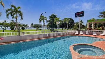Una piscina con hidromasaje, rodeada de palmeras y vista al océano.
