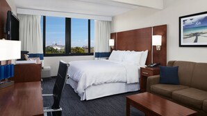 A hotel room with a large bed, a desk, a chair, a sofa, a TV, and a window with a view of the city. - Four Points by Sheraton Fort Lauderdale Airport/Cruise Port (Fort Lauderdale)