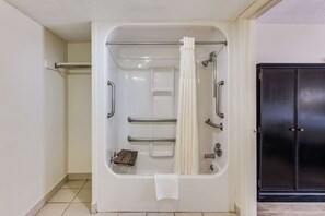A bathroom with a bathtub, a towel rack, a shower curtain, and a door.