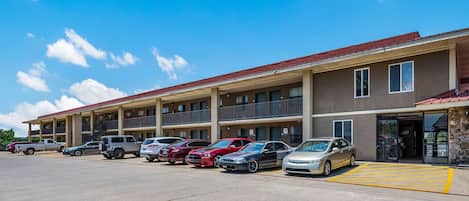 Un hôtel à plusieurs étages, doté d’un parking et où plusieurs voitures sont garées devant.