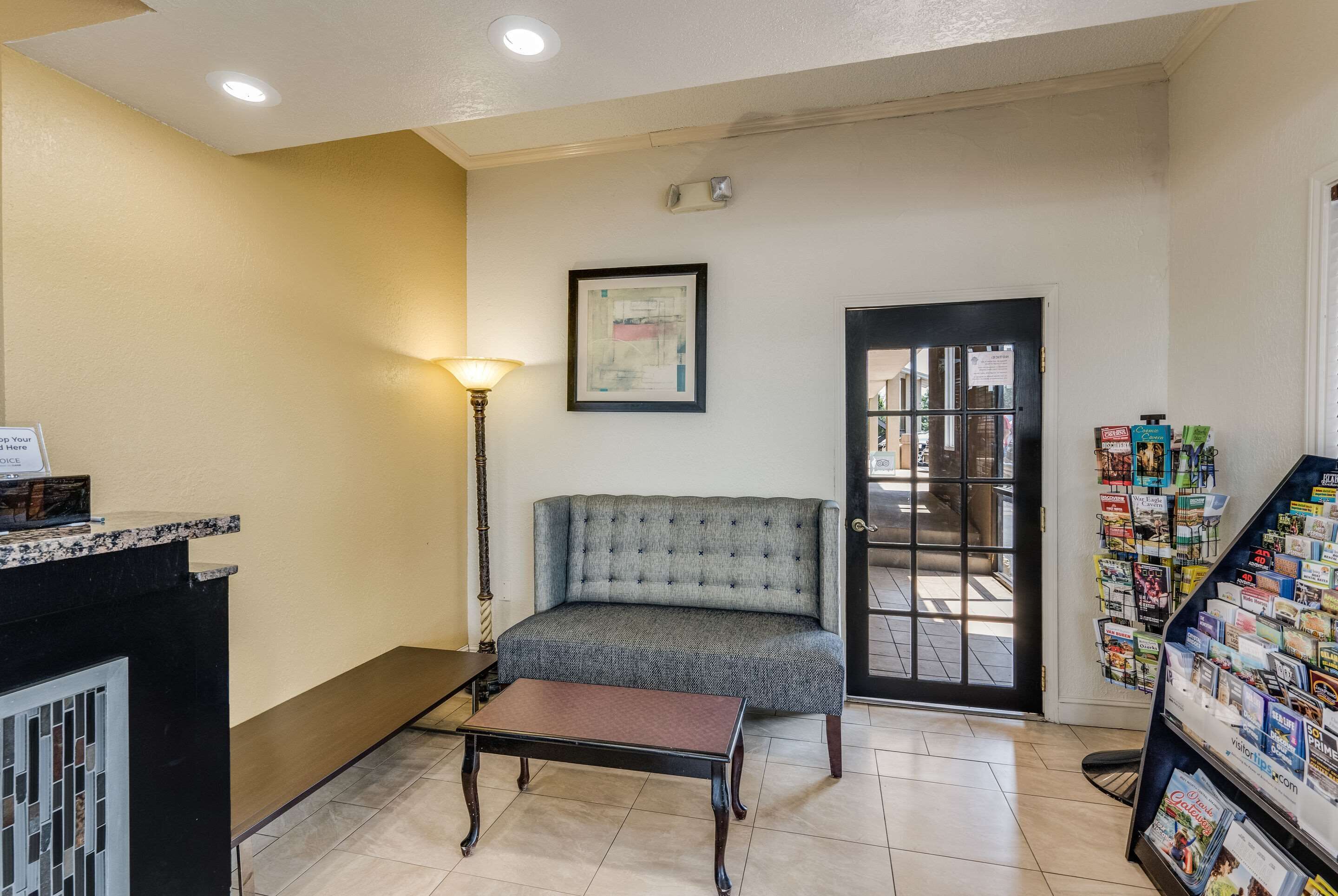 Un área de recepción con un sofá, una mesa, una lámpara, una puerta y un mueble para revistas.