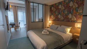 A hotel room with a large bed, a desk with a chair, a small table, and a mirror. - The Originals City, Ara Hôtel (Landerneau)