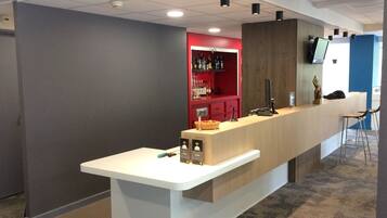 Un espace d’accueil avec un comptoir, un bar rouge et un écran de télévision.