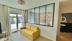 A modern living room with a yellow sofa, a large window, and a mirrored wall. - The Originals City, Ara Hôtel (Landerneau)