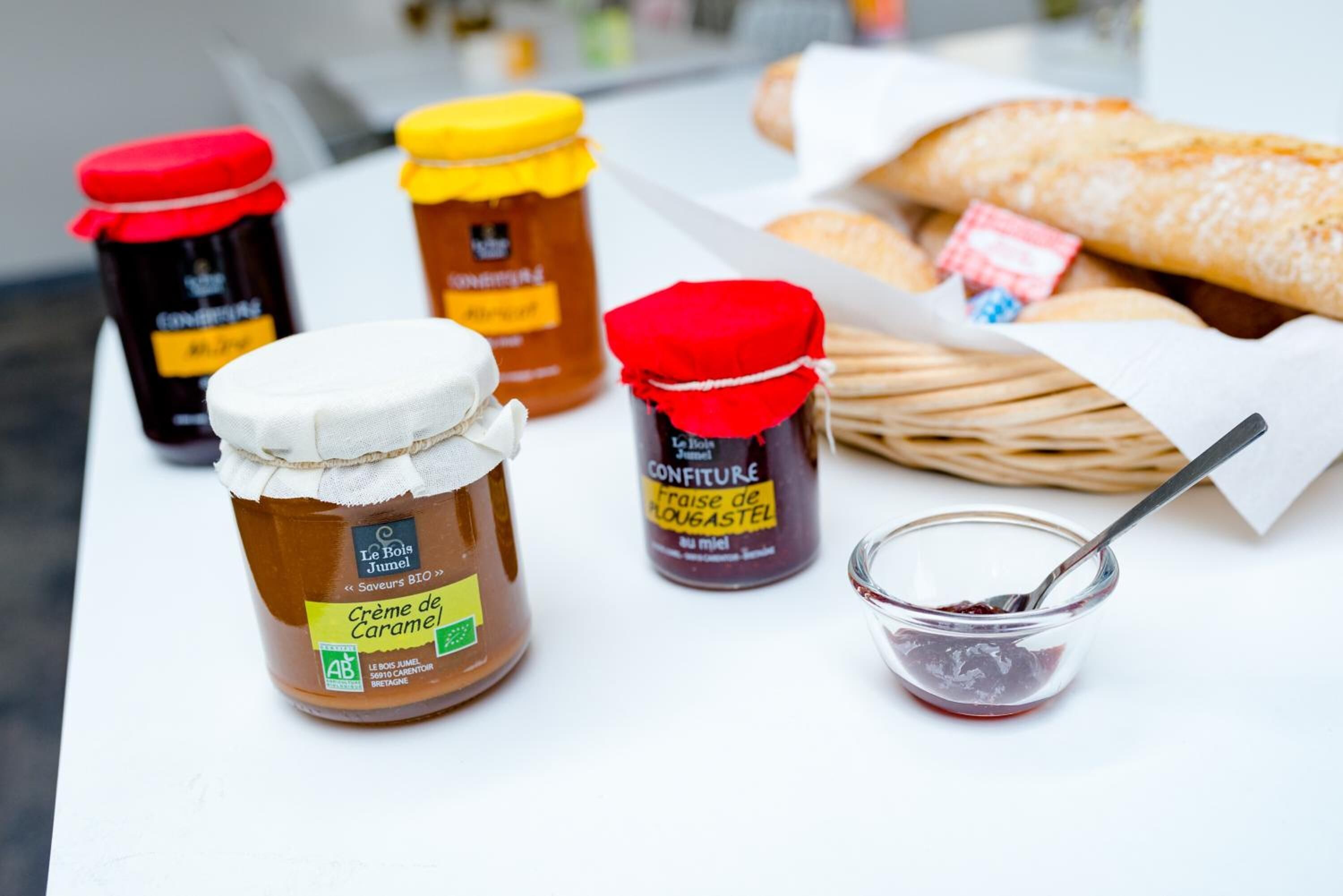 Vier potten honing en een kleine schaal honing op een tafel met brood.