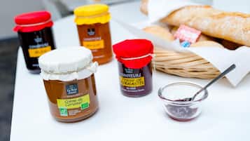 Vier potten honing en een kleine schaal honing op een tafel met brood.