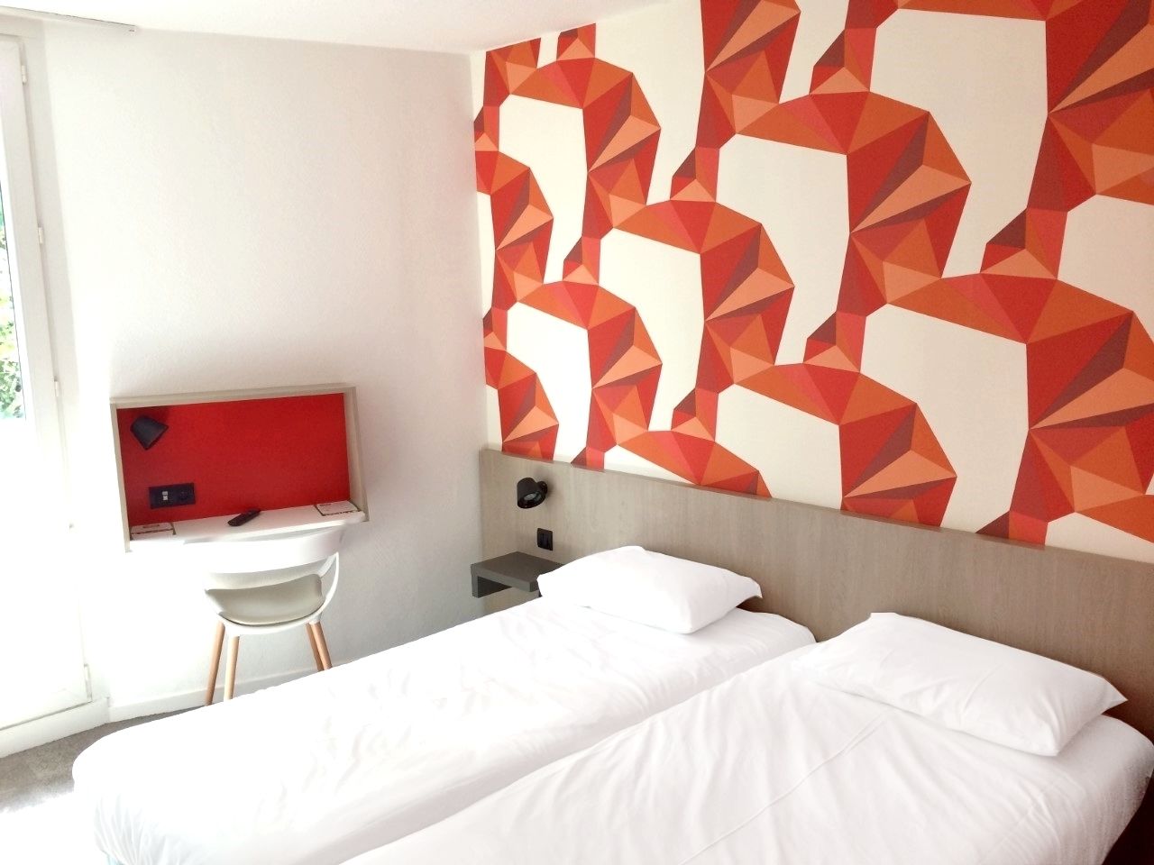 A hotel room with two beds, a desk, and a TV.