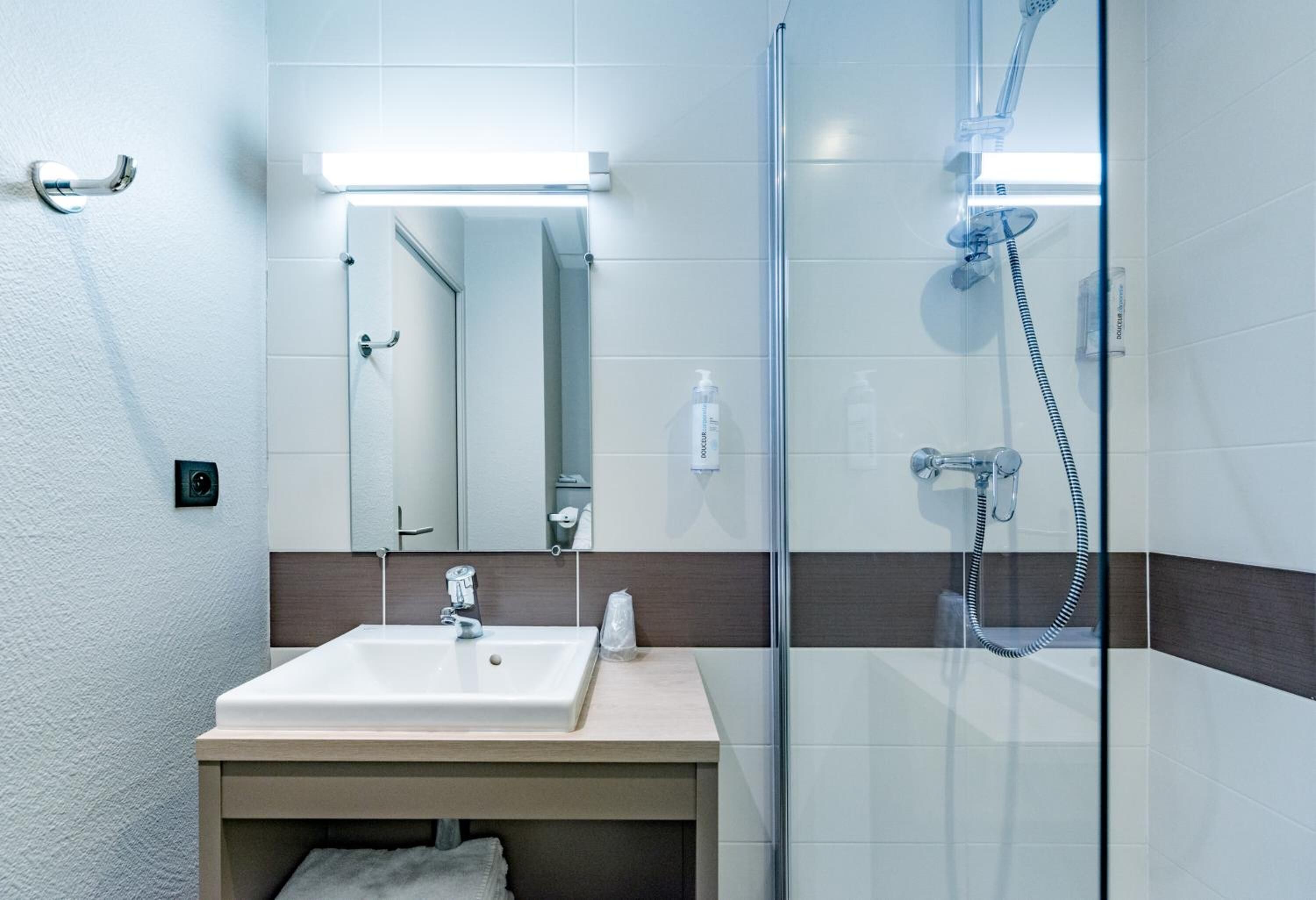 A modern bathroom with a glass-enclosed shower, a white sink, and a mirror above it.