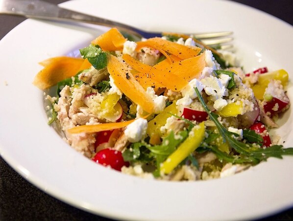 A plate of food with various ingredients including greens, carrots, and possibly chicken, served on a white plate.