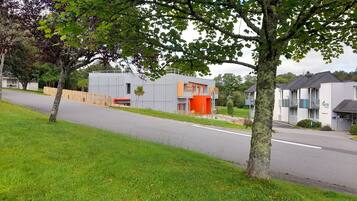 Un hôtel moderne doté d’un toit plat, d’un mur d’accent rouge et d’un petit espace extérieur aménagé pour s’asseoir.