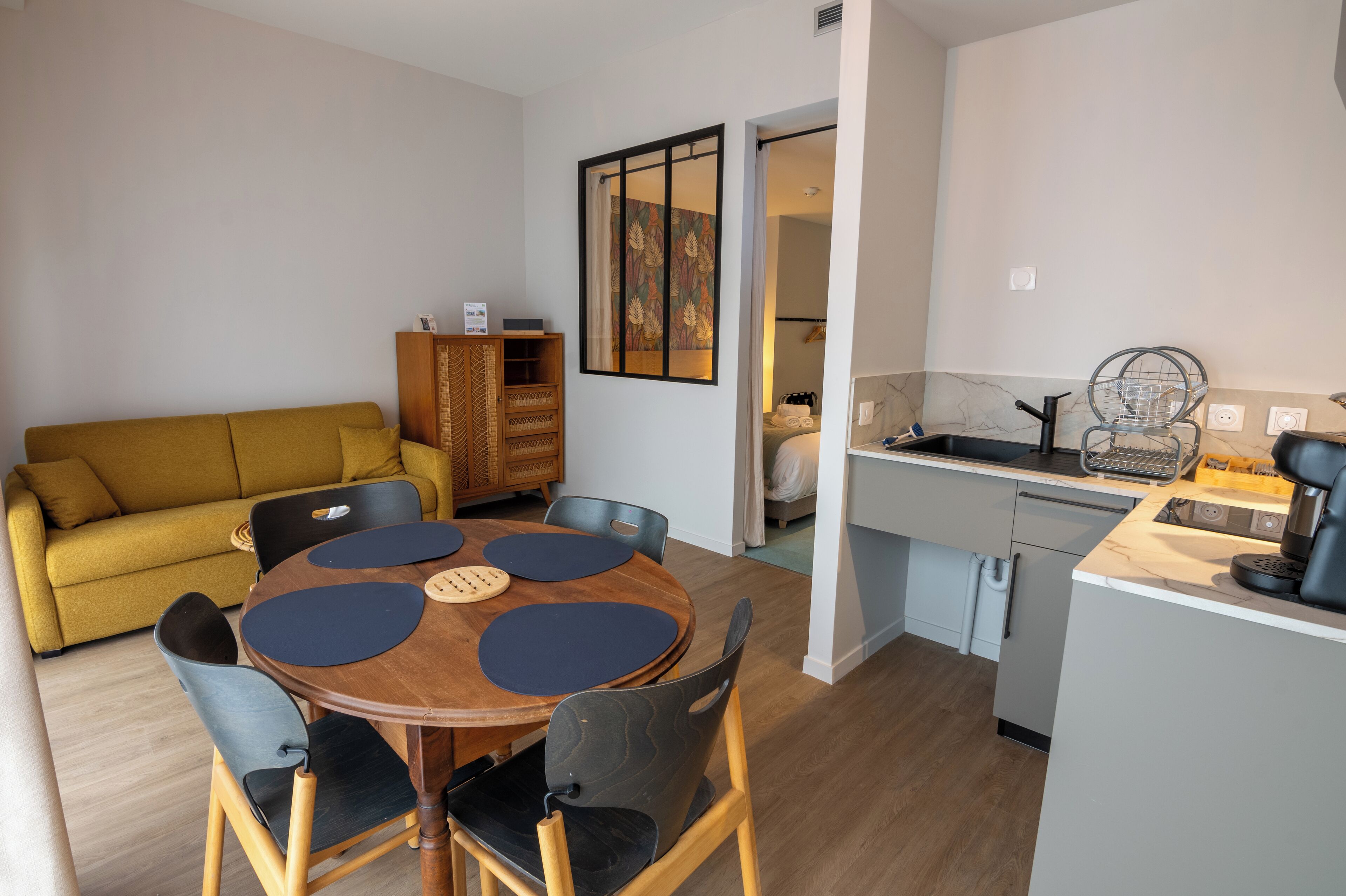 A compact living space with a dining area, kitchenette, and a sofa.