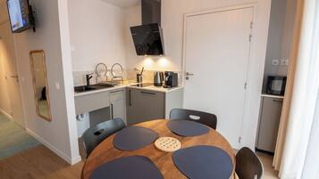 A compact kitchen with a round dining table, a built-in oven, and a TV mounted on the wall.