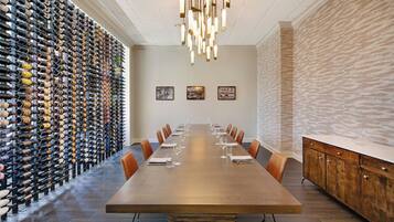 Une salle de conférence avec une longue table, des chaises et un meuble à vin le long d’un des murs.