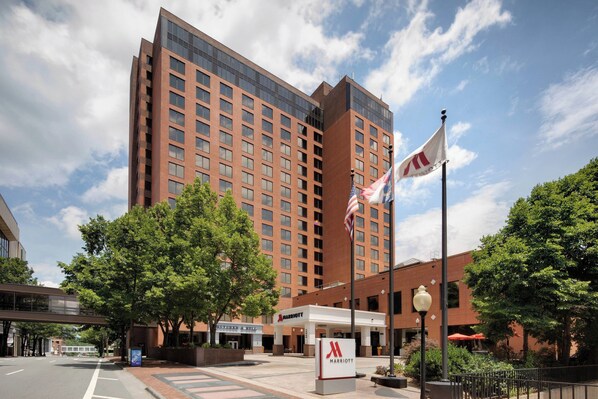 A Marriott hotel with a modern brick facade, a flagpole with the American flag, and a signboard with the Marriott logo.