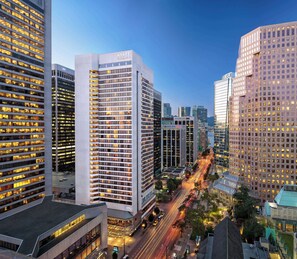 Un moderno hotel de gran altura con un llamativo letrero de "HYATT REGENCY", rodeado de otros edificios altos y una calle concurrida con estelas de luz de vehículos en movimiento.