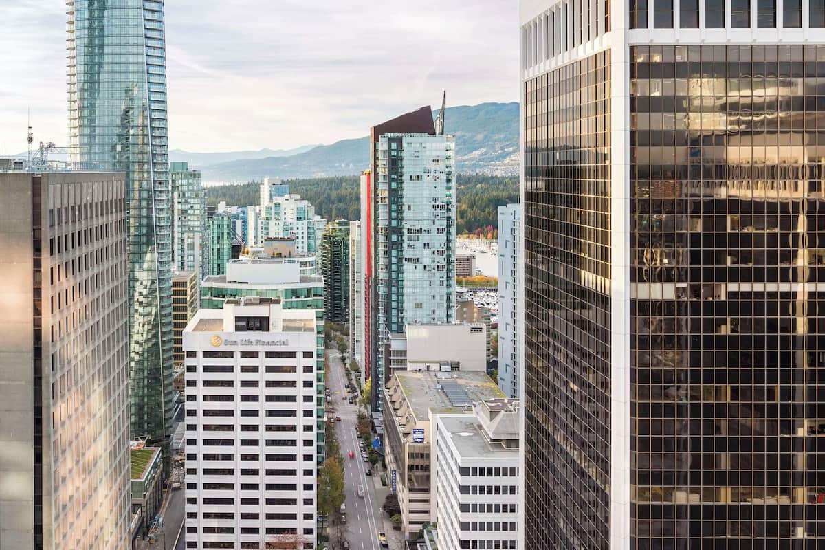 A high-rise building with a glass facade, surrounded by other modern buildings and a busy street below.