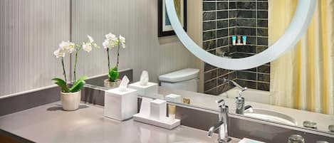 Un baño moderno con un espejo grande, un lavabo, un perchero para toallas y una estantería con toallas.