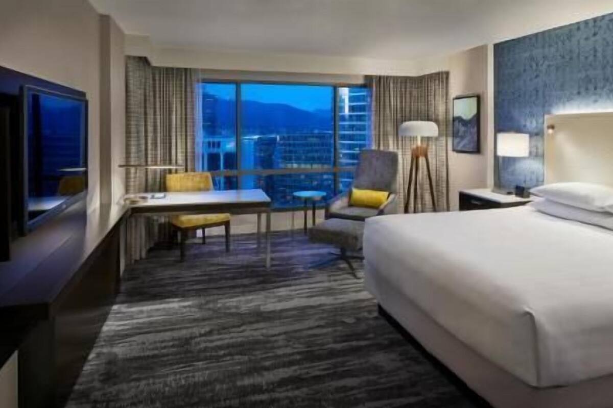 Une chambre d  ’hôtel équipée d’un lit, d’un bureau, d’une chaise, d’une télévision et d’une fenêtre donnant sur la ville.