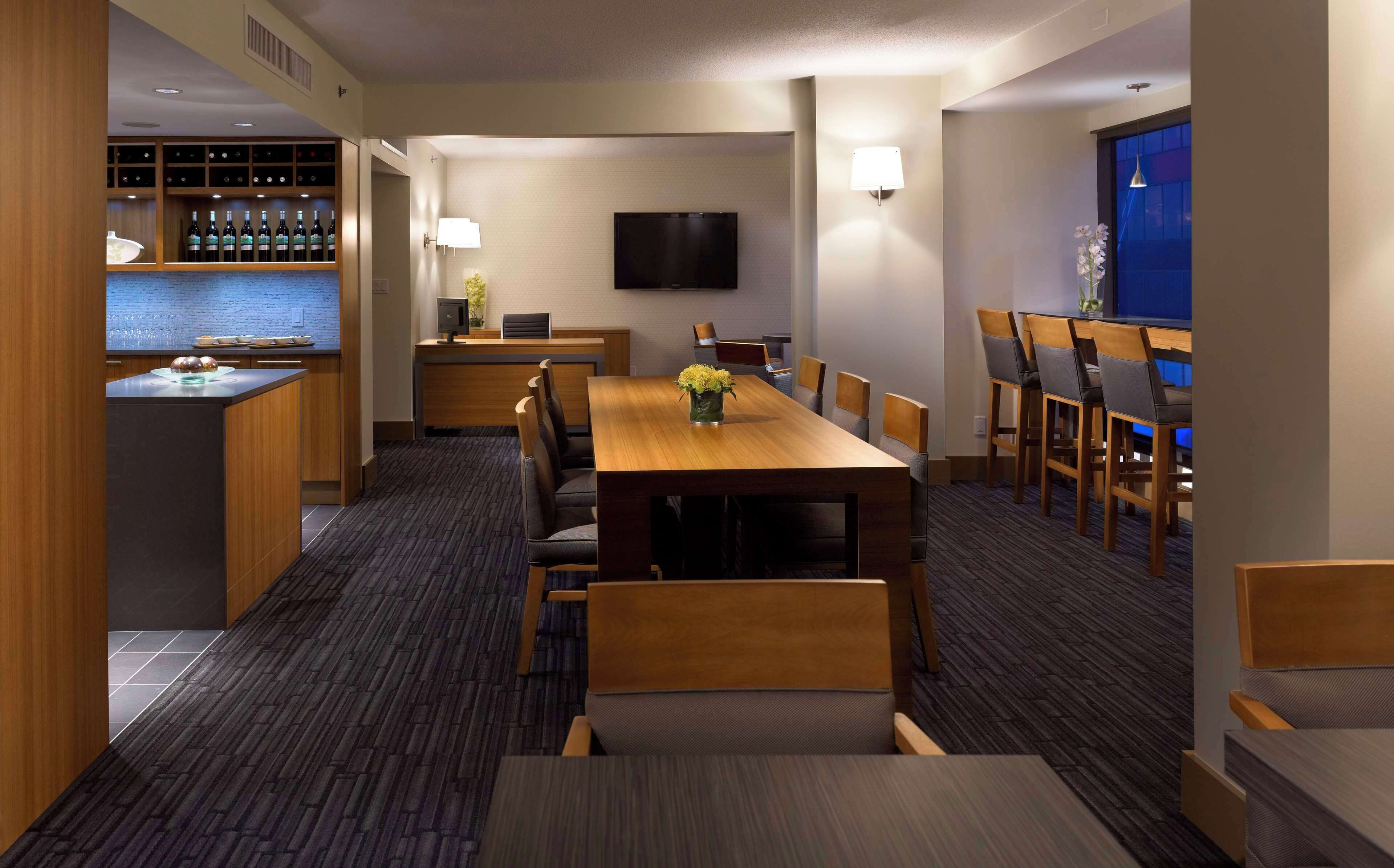 A hotel room with a dining area, a bar, and a TV.