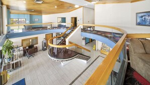 Eine großzügige Hotelhalle mit einer zentralen Treppe, einer Rezeption und einer Sitzecke.
