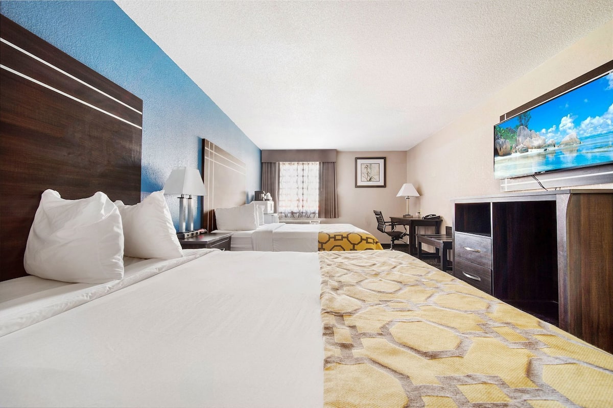 Habitación de hotel con cama, escritorio, televisión y vistas al exterior.
