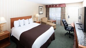 Une chambre d’hôtel avec un grand lit, un bureau, une chaise, une lampe et une armoire.