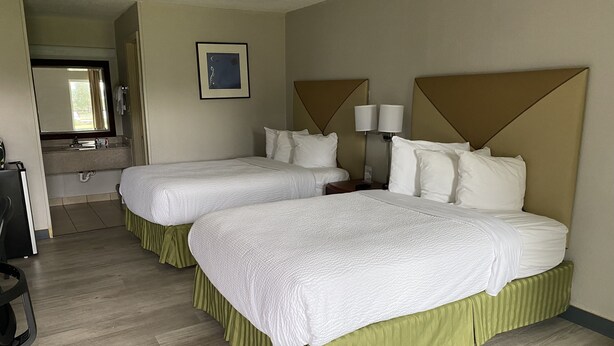 Ein Hotelzimmer mit zwei Betten, einem Badezimmer und einem Schreibtisch.