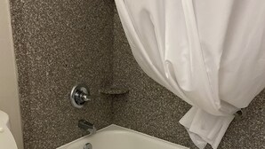 Ein Badezimmer mit Badewanne, Toilette und einer Wand aus Granit.