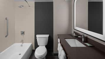 Une salle de bain moderne équipée d’une baignoire, de toilettes et d’un meuble-lavabo avec un miroir.