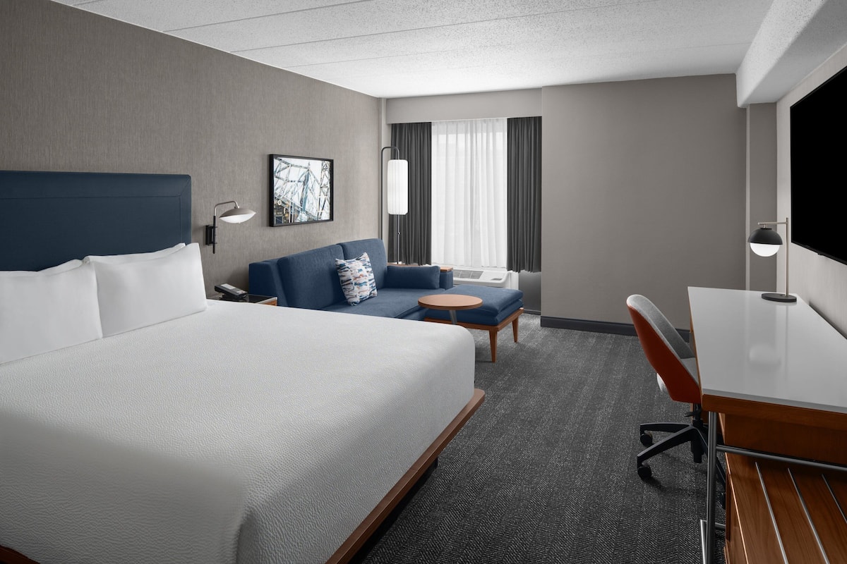 Een hotelkamer met een groot bed, een bank, een tafeltje, een bureau en een televisie.