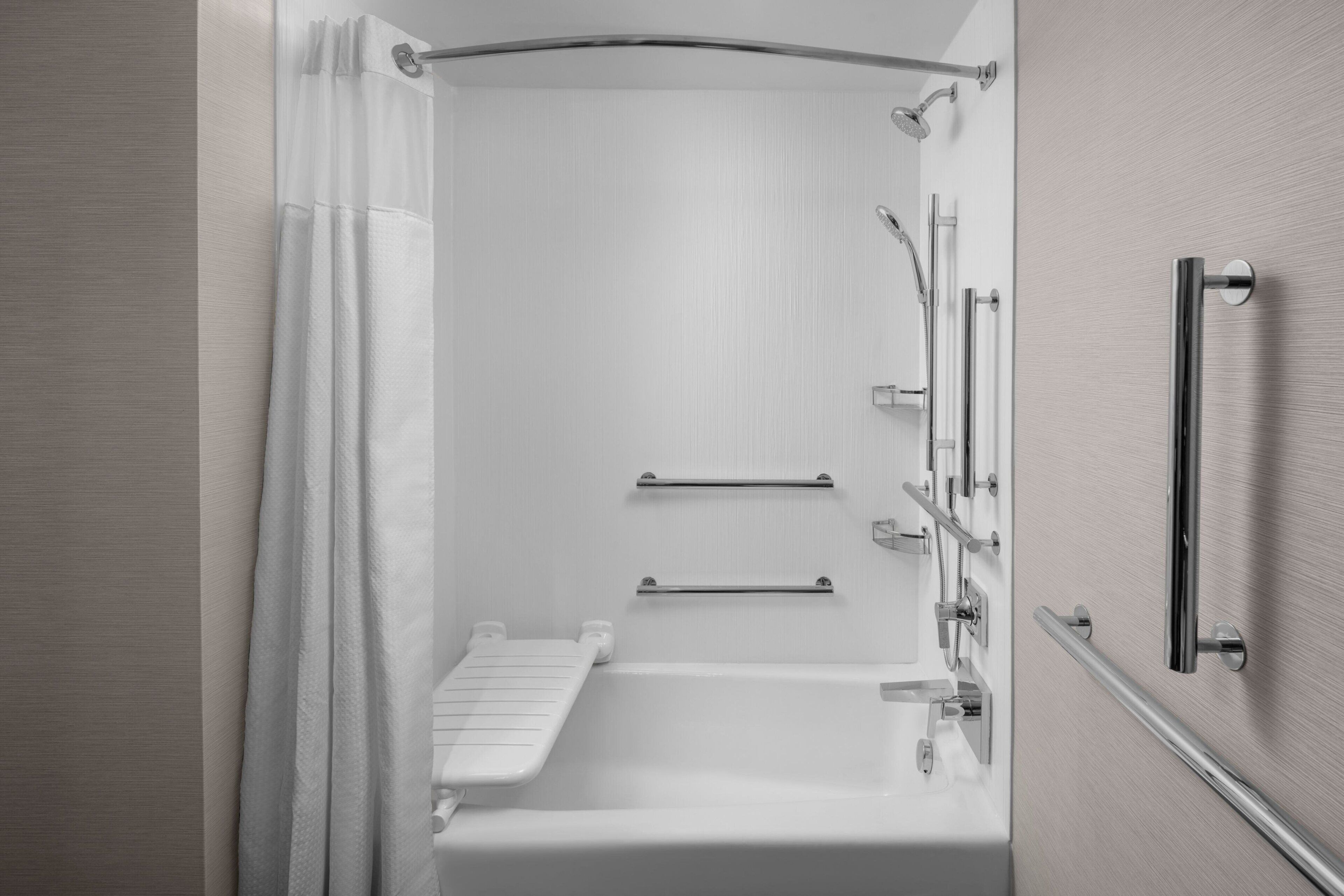 A modern bathroom with a walk-in shower, grab bars, and a towel rack.