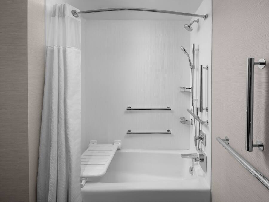 A modern bathroom with a walk-in shower, grab bars, and a towel rack.