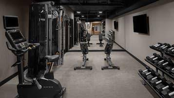 Une salle de sport équipée de machines de cardio, de matériel de musculation et d’haltères.