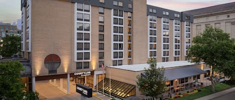 A Courtyard by Marriott hotel with a modern design, featuring a large glass entrance, outdoor seating area, and a parking lot.