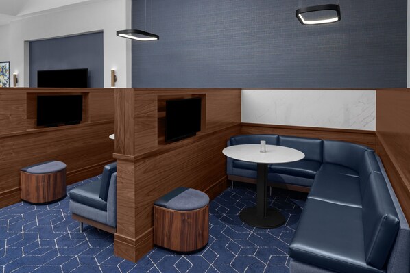 A modern lounge area with a sofa, a round table, and two ottomans.