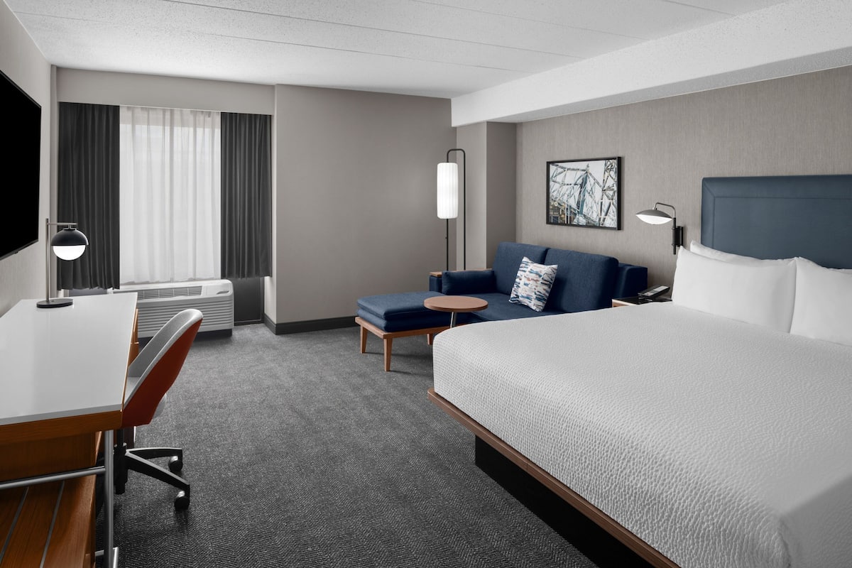 Een hotelkamer met een bed, een bureau, een stoel, een bank, een kleine tafel en een televisie.
