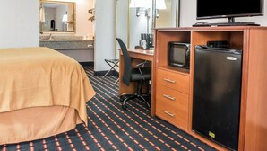 A hotel room with a bed, a desk with a computer, a refrigerator, a television, and a mirror. - Quality Inn Marianna South (Marianna)