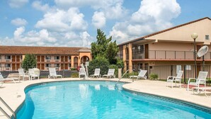A swimming pool with lounge chairs and a building with a tiled roof in the background. - Quality Inn Marianna South (Marianna)
